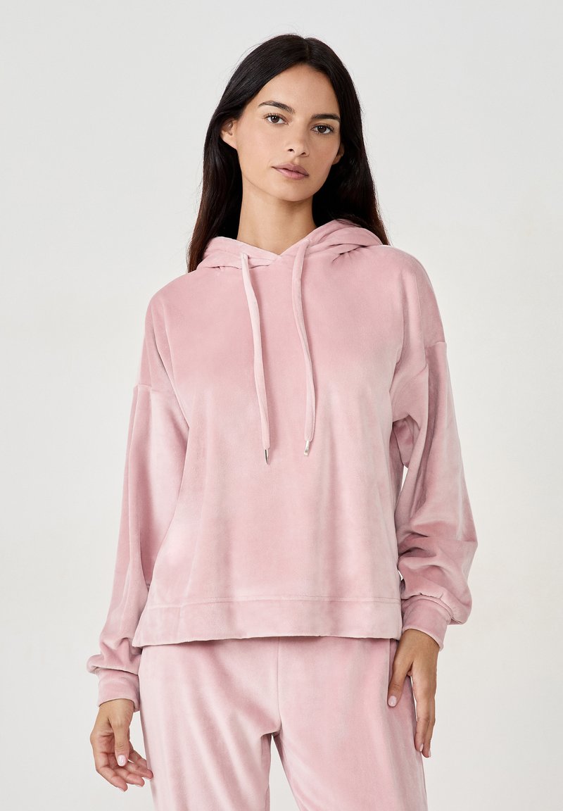 Felpa in velour rosa con una vestibilità ampia, cappuccio con cordino e maniche lunghe. Texture morbida e design minimalista con orlo dritto.