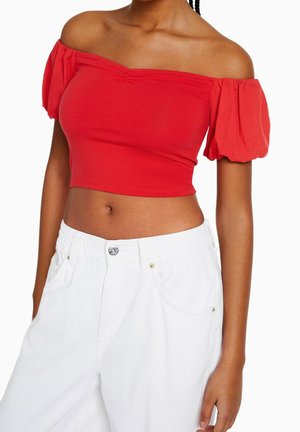 Rood cropped top met off-shoulder pofmouwen. Gemaakt van rekbare katoen, met een geplooide halslijn en een gladde textuur. Gecombineerd met witte broek.