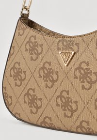 Brązowa torba na ramię z płótna z tłoczonym wzorem logo, złotymi trójkątnymi elementami metalowymi oraz zakrzywioną górną krawędzią z zamkiem błyskawicznym.