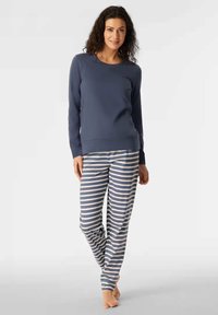 Maglietta a manica lunga di colore navy con scollo rotondo abbinata a pantaloni del pigiama grigi e bianchi a righe. Tessuto morbido, vestibilità rilassata e design minimalista.