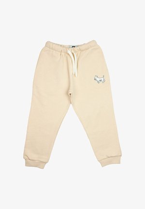 Pantaloni della tuta beige per bambini con vita elastica, coulisse bianca, polsini alle caviglie e piccolo cane bianco ricamato sulla coscia sinistra.