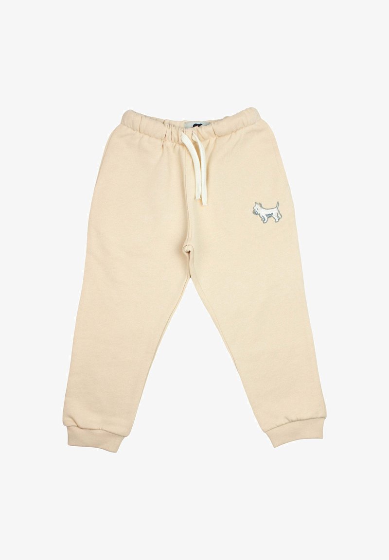 Pantalon de sport beige pour enfants avec taille élastique, cordon blanc, chevilles resserrées et petit chien blanc brodé sur la cuisse gauche.