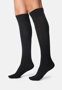 Calcetas negras hasta la rodilla, hechas de una tela suave con un puño acanalado, que cuentan con un diseño de puntera sin costuras. Adecuadas para diversas ocasiones.
