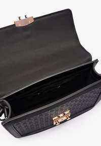 Sac à main noir avec un design texturé et des finitions dorées. L'intérieur est doublé de tissu noir, avec des compartiments pour s'organiser.
