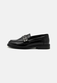 Svarte skinnloafers med en dekorativ stropp med sølvfargede nagler, rund tå og en lav profilsåle. Jevn tekstur, klassisk design.