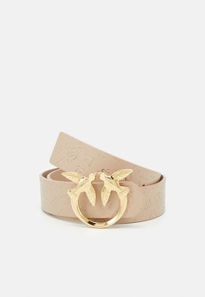 Beige leren riem met geperste patronen en een gouden gesp met twee vogels die elkaar aankijken in een cirkelvormig ontwerp.