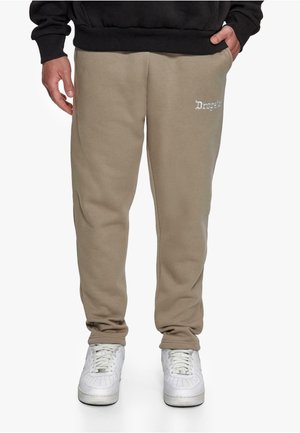 Beige joggebukser med elastisk midje og mansjetter, med et lite hvitt brodert logo på venstre lår. Glatt bomullsstoff.
