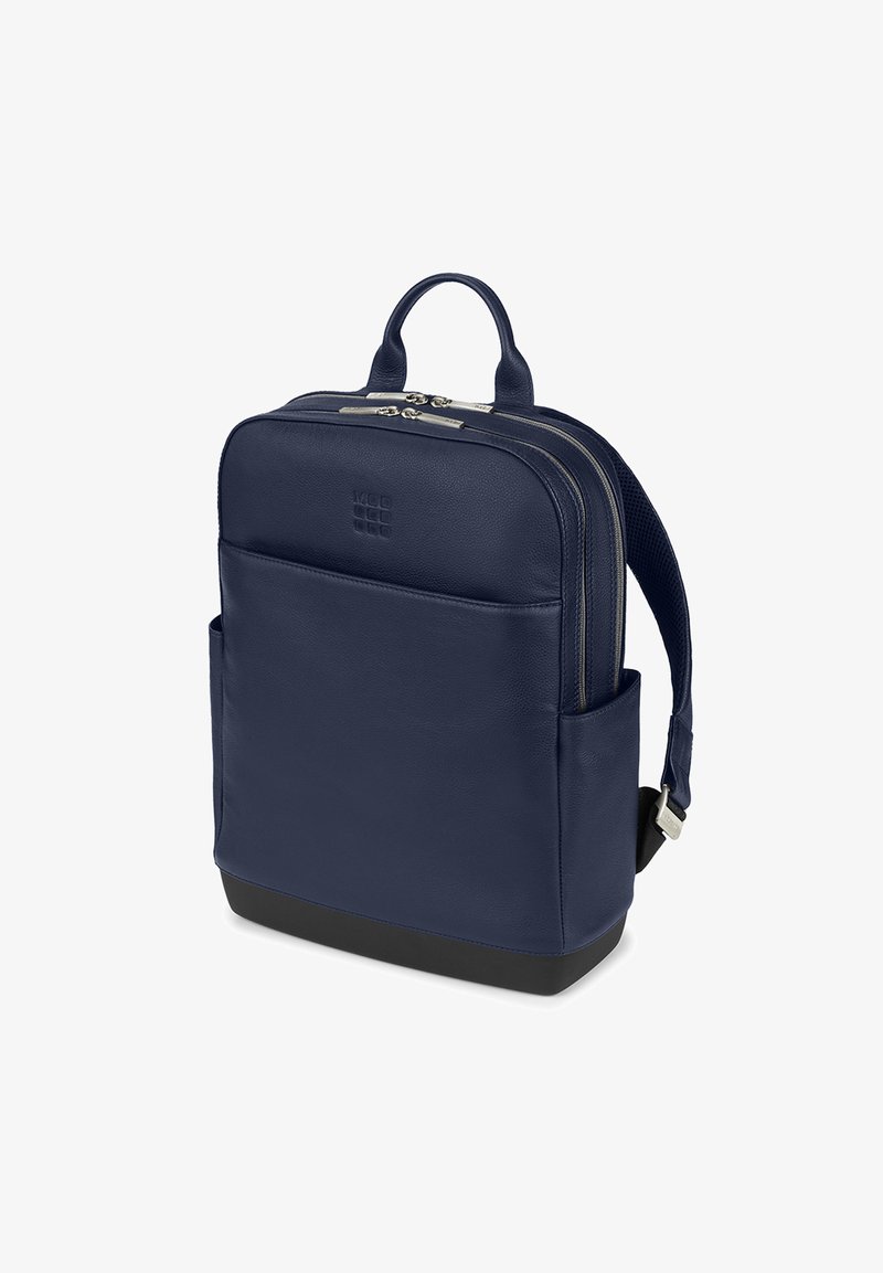 Zaino in pelle blu navy con doppie cerniere, manico superiore, tasca frontale e spallacci imbottiti. Presenta una forma rettangolare elegante e una finitura per anni.
