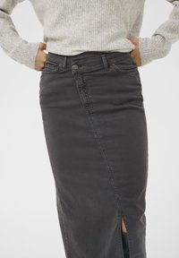 Čierna denimová sukňa s rovnými nohavicami, s postranným rozparkem. Tkanina má hladkú textúru a pás má klasické zapínanie na gombík.