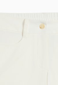 Λευκό παντελόνι με κούμπωμα κουμπιού, θηλιές για ζώνη και ορατή μπροστινή τσέπη στην περιοχή της μέσης.