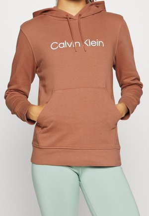 Felpa marrone realizzata in tessuto morbido con una tasca frontale, caratterizzata da un logo bianco "Calvin Klein" sul petto e un cappuccio con cordoncino.