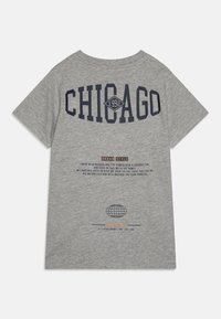 Pelēks kokvilnas T-krekls ar uzrakstu "CHICAGO 1992" jūras zilā krāsā, zem kura ir pilsētai raksturīgs teksts un globusa grafika. Īsas piedurknes, brīvs griezums.