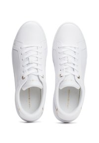 Baskets blanches synthétiques à texture lisse, bout arrondi, design à lacets, avec des accents dorés subtils sur les œillets et le branding.