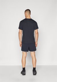 Mørk marineblå T-skjorte og matchende trening shorts med hvite detaljer. Shortsene har en avslappet passform og er laget av lett materiale.