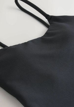 Black tank top with thin straps, made from smooth, stretchy fabric. Features a simple design with no visible patterns or accents.