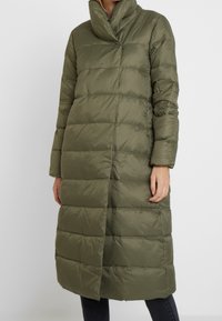 Abrigo largo acolchado de color verde oliva con un cuello alto, diseño acolchado y cremallera de longitud completa. El material parece suave y resistente al agua.