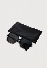 Čierne štvorcové slnečné okuliare s tmavými šošovkami, ktoré majú štíhly, lesklý rám. Sú súčasťou čierneho koženého puzdra s vyrazeným logom.