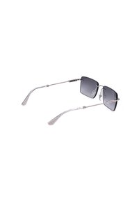 Lunettes de soleil rectangulaires sans monture avec des branches fines en métal argenté et des verres teintés foncés, inclinées pour montrer l'intérieur et les détails des branches.