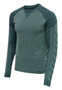 Vihreä pitkähihaainen paita, jossa on teksturoitu vartalo ja yksiväriset hihat. Hihoissa on erottuva viistokuvio ja pyöreä kaula-aukko.