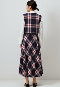 Karirani dvodijelni outfit sa prilagođenim, kratkim sakoom i dugom, lepršavom suknjom. Boje uključuju tamnoplavu, crvenu i bijelu. Izrađen od mekanog, teksturiranog materijala.