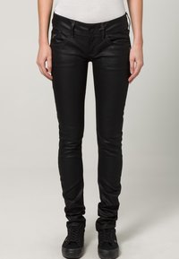 Svarta smala jeans gjorda av ett mjukt, stretchigt tyg. Har en knappstängning, framfickor och subtila sömdetaljer.