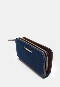 Blauwe denim portemonnee met een bruin leren rits en afwerking, met een gouden logo aan de voorkant en een gestructureerd oppervlak. Ritscompartimenten zijn zichtbaar.