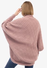 Poncho lavorato a maglia rosa con un motivo a diamante, polsini a coste e un design fluido, che presenta una texture morbida e lati aperti per il massimo comfort.