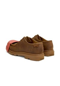 Scarpe di camoscio marrone con punta tonda e suola in gomma, caratterizzate da un accento corallo sul davanti e dettagli di cucitura industriale.