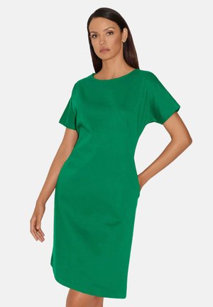 Grünes Kurzarmkleid mit Rundhalsausschnitt, gerade geschnitten und mit Seitentaschen. Glattes Material mit leicht strukturierter Oberfläche.