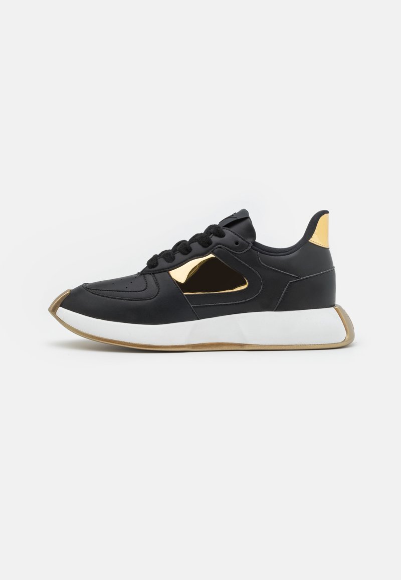 Černé tenisky se zlatými akcenty, s hladkým koženým svrškem, zaoblenou špičkou a silnou bílou podrážkou s texturovaným povrchem.