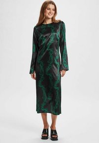 Rochie din satin negru cu mâneci lungi, având un model verde spiralat. Este croită drept și se termină la jumătatea gambei, fiind asortată cu tocuri groase negre.