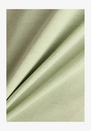 Weicher, hellgrüner Stoff mit feiner Strickstruktur, in sanften Falten und glatten, gleichmäßigen Nähten präsentiert.