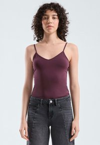 Bordeauxrood tanktop met dunne bandjes, V-hals ontwerp, strak aansluitende textuur. Draag het met hoog-getailleerde donkergrijze jeans. Simpele en elegante uitstraling.