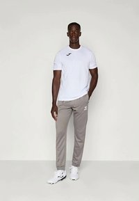 Camiseta branca de manga curta com logo, calças de desporto cinzentas e sapatos brancos. Design simples com um corte descontraído e textura de tecido suave.