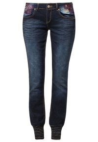 Tumman siniset farkkulegginsit, joissa on elastiset hihnat, kukka-ompelut etutaskuissa ja nappikiinnitys vyötäröllä.