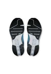 Chaussures de sport avec une semelle noire et argentée, texturée pour une meilleure adhérence, arborant un design en maille bleue sur le dessus et des éléments de coussinage prononcés.