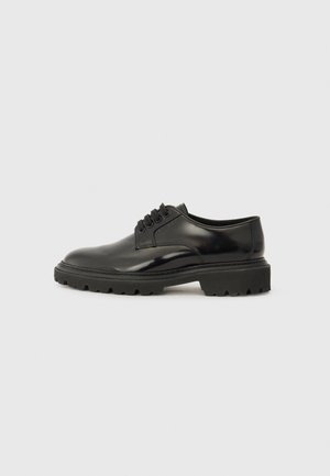 Scarpa nera in pelle con lacci, finitura liscia, punta arrotondata e suola in gomma spessa con un motivo di battistrada testurizzato.