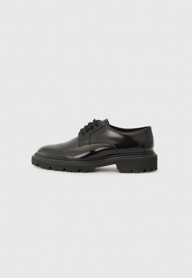 Chaussure noire en cuir à lacets avec une finition lisse, un bout arrondi et une semelle en caoutchouc épaisse avec un motif de semelle texturé.