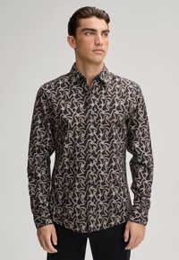 Maglietta nera a maniche lunghe caratterizzata da un intricato motivo a spirale bianco e beige, colletto button-down e design aderente.