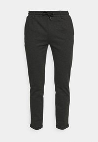 Pantalon de jogging gris foncé en matériau doux, avec une taille élastique et un cordon de serrage, et deux poches latérales. Coupe ajustée.