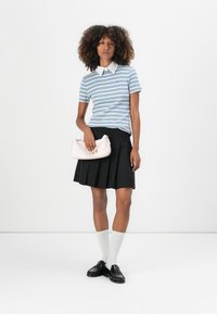 Stripete lys blå og hvit kortermet polo, hvit krage, sammen med et svart plisserte skjørt, holder en myk rosa veske, hvite sokker, svarte loafers.