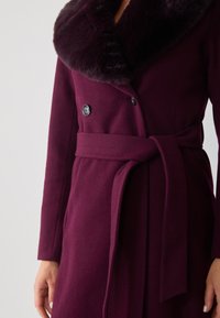 Bordeaux wollen mixen jas met een faux fur kraag, dubbele knopen, zijriem en een strakke, getailleerde silhouet.