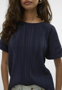 Marineblå plisseret top lavet af let materiale, med rund halsudskæring og korte ærmer, i en afslappet pasform og tekstureret overflade.