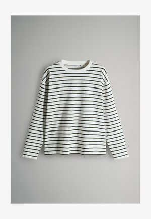 Chemise blanche à manches longues avec des rayures horizontales noires, encolure ronde et coupe décontractée, présentée sur un fond gris clair uni.