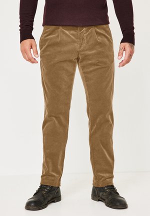 Brown corduroy trousers with a textured surface, featuring front pleats and side pockets, paired with black lace-up boots.