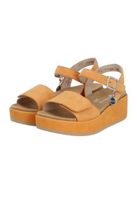 Orange suede platform sandals with two wide straps, one adjustable buckle strap, and a flat rubber sole. Features a charm on the buckle.