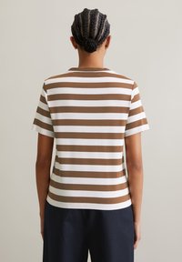 Brown and white striped t-shirt with a round neckline, short sleeves, and a relaxed fit, made from soft fabric. Visible stitching details.