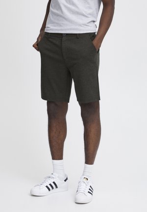 Mørkegrå shorts med en glat stoffinish, der har sidelommer, knaplukning og en knælang skæring, parret med hvide sneakers.