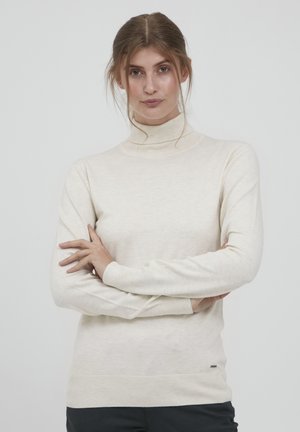 V krém színű turtleneck pulóver, puha anyagból készült, hosszú ujjakkal, bordás mandzsettákkal és finom textúrával, amelyet egy apró logó díszít.