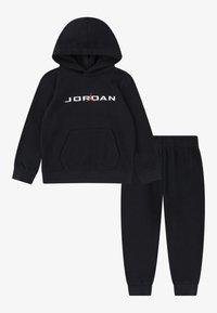 Fekete kapucnis pulóver és az ahhoz illő melegítőnadrág szett, puha anyagból. Elől zseb található, a "JORDAN" logó fehér színben, piros részletekkel.